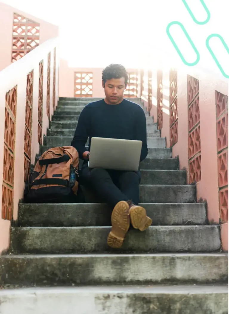 An image of a man using his laptop on a concrete stairway outdoors.