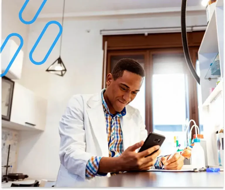 An image of a pharmacist copying information from their phone to a document.