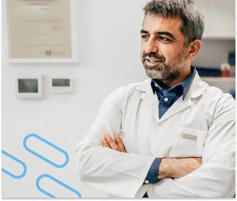 An image of a man with his arms crossed and appearing to have frinedly conversation with someone off camera. On the bottom-lefthand corner are three blue diagonal pill graphics.