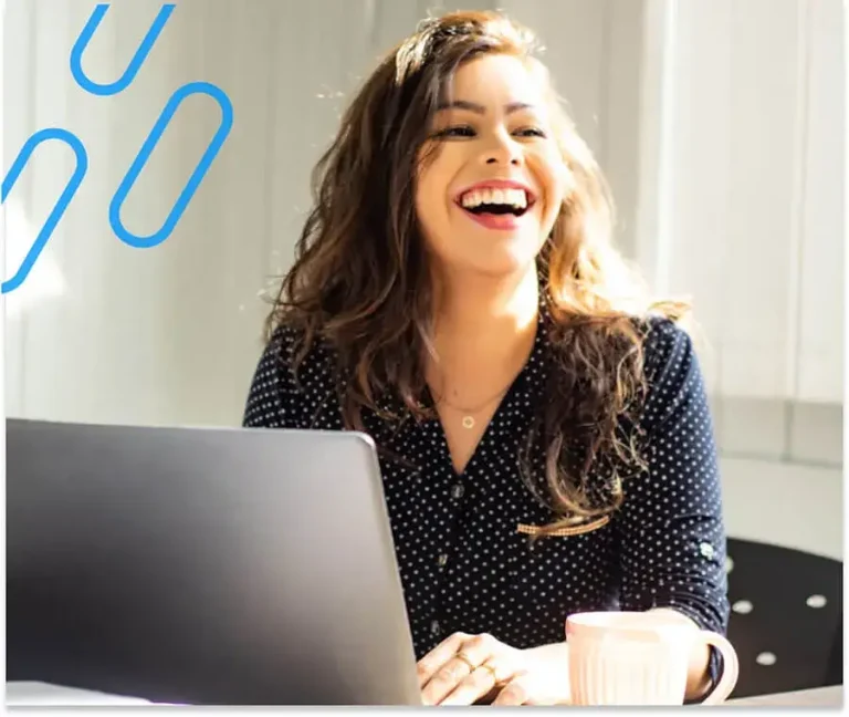 An image of a lady smiling in front of her laptop.