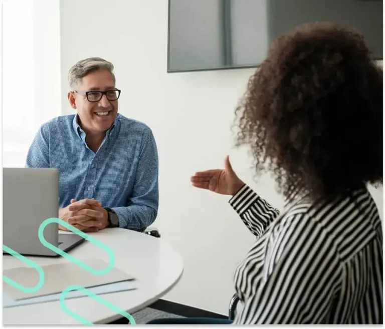 An image of two individuals having a conference inside of an office setting.